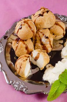 Profiteroles dessert served with fresh cream and chocolate syrup