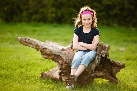 Girl sitting on a tree trunk at the golden hour on a warm summer day