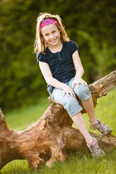 Girl sitting on a tree trunk at the golden hour on a warm summer day