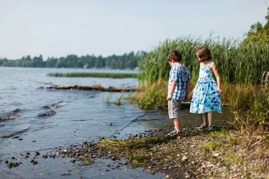 Brother and sister standing by a lake on a warm summer day