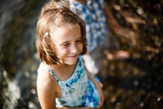 Girl smiling in the sun while having her feet in the water