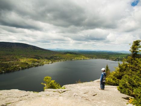 Boy standing on a cliff high above a lake