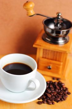 Cup of hot coffee with coffee grinder and beans 