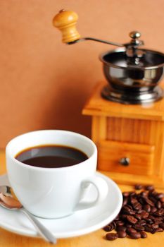 Cup of hot coffee with coffee grinder and beans 