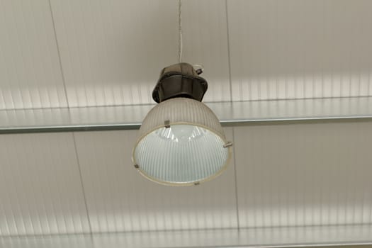 Industrial ceiling reflector with aluminium lamp vessel hanging from the roof