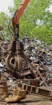 inustrial machine with scrap metal grapple in front of scrap iron