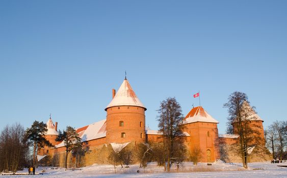 Beautiful sunset sunlight on Trakai castle in winter and people tourists recreate near it.
