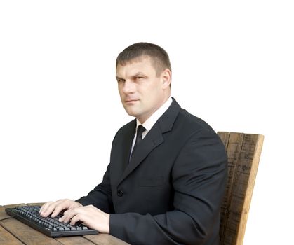 The man with the computer keyboard sits at a wooden table