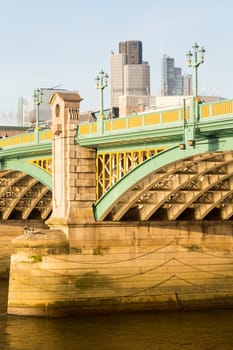 Girders supporting Southwark Bridge across the Thames river in London with setting sun lighting the painted ironwork