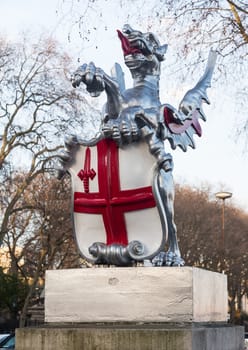 Dragon with red cross on shield marking the boundary of the City of London in England by roadside