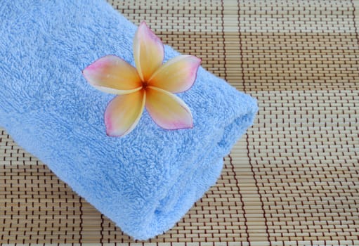 blue towel and plumeria flower on wooden background