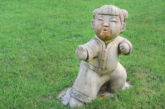 Traditional child Chinese style statue on the grass in garden