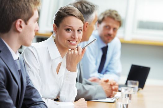 Portrait of a pretty young businesswoman smiling in a meeting with her colleagues in background