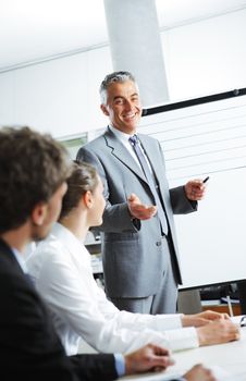 Smiling businessman discussing plans with his colleagues in board meeting