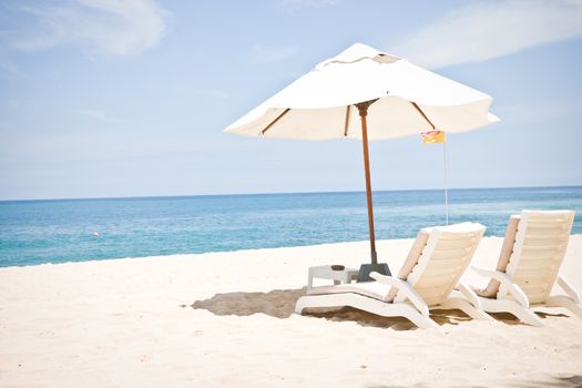 Idyllic beach scene with umbrella and two lounge chairs