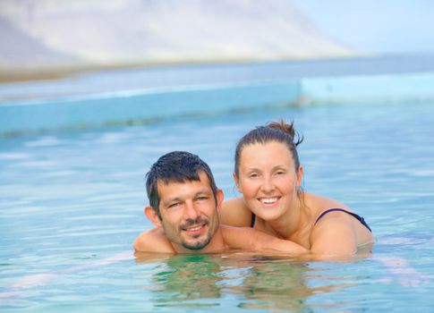 Smiling happy couple in geothermal mineral pool. Iceland