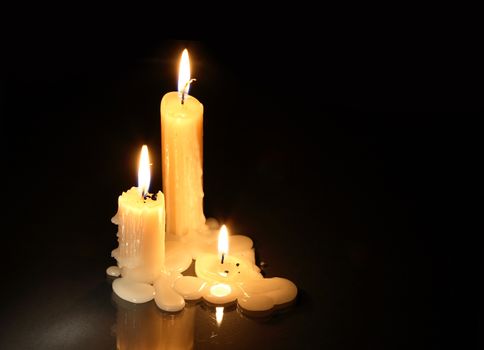 Three lighting candles on dark background with free space for text