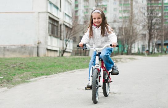 little girl with bicycle on road