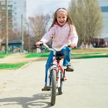 Little girl on a bicycle in summer park
