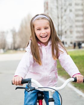 little smiling girl with bicycle on road