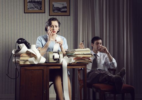 Woman works on home finances. Man relaxed in chair drinking whiskey