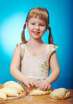 Smiling little girl kneading dough at kitchen with baking a pie