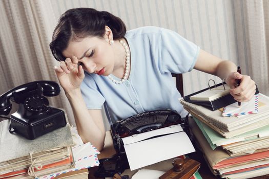 Tired businesswoman is sitting at a table full of paperwork