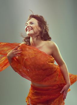 Beautiful woman in  waving fabric.Portrait of young dancing girl