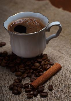 Coffee cup with cinnamon and coffee beans background