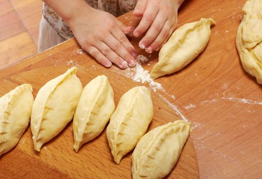 Smiling little girl kneading dough at kitchen .Detail of hands kneading dough