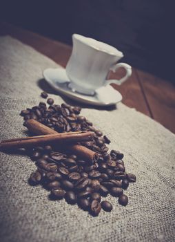 Coffee cup with cinnamon and coffee beans background