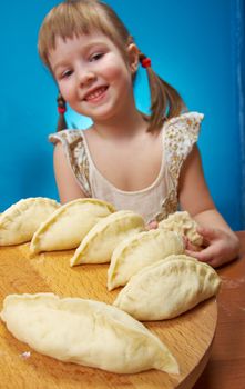 Smiling little girl kneading dough at kitchen with baking a pie