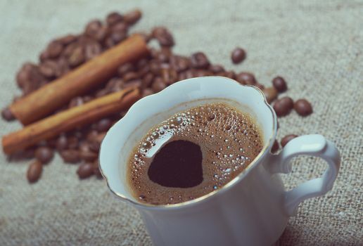 Coffee cup with cinnamon and coffee beans background