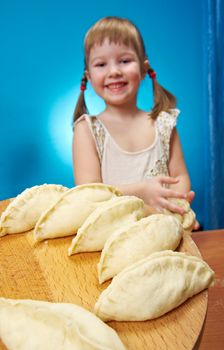 Smiling little girl kneading dough at kitchen with baking a pie
