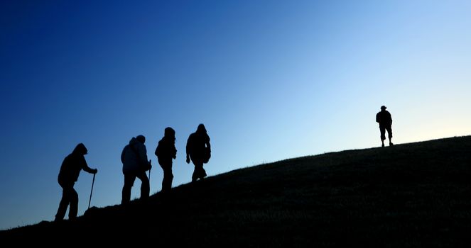 Group of tourists take to the mountains. Silhouette