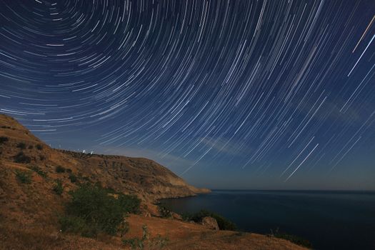 Night landscape, night sky with moving stars over the sea. Mountain Meganom, Crimea, Ukraine
