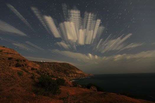 Night landscape, night sky with moving stars over the sea. Mountain Meganom, Crimea, Ukraine
