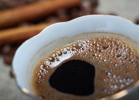 Coffee cup with cinnamon and coffee beans background