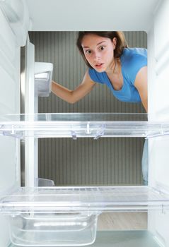 Young woman looking in his empty fridge