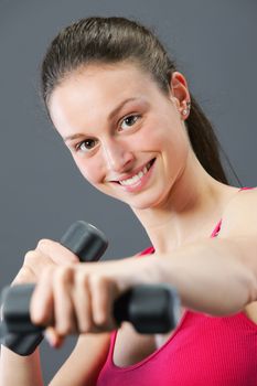 Portrait of beautiful young woman lifting dumbbells during exercise