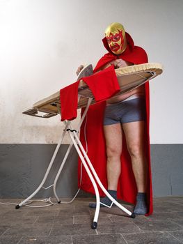 Photograph of a Mexican wrestler or Luchador ironing his red tights before his fight.
