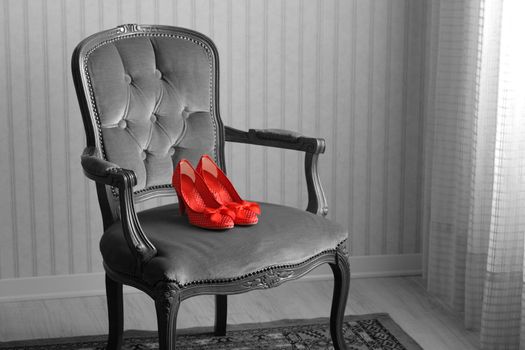 Baroque chair and red women's shoes  in an empty room