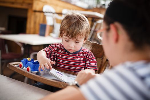 Mother reading to her son while waiting at a restaurant