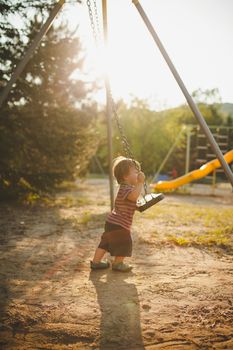 Infant on a swing at sunset