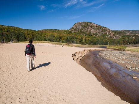 Woman walking on the sand near a river in Acadia National Park