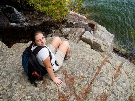 Woman sitting on a cliff over a lake in Acadia National Park