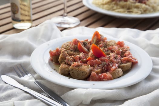 Version of Greek Dakos appetizer made with rusk topped with tomatoes with olives, spices and olive oil.