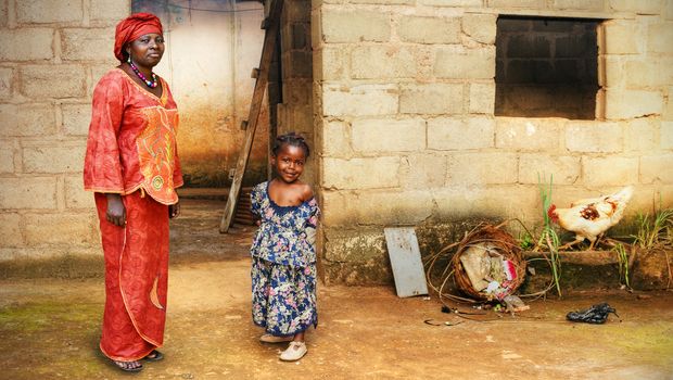 Black African little girl and her mother in traditional clothing at home