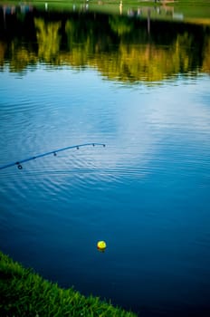 fishing rod with float held by fisherman on a lake