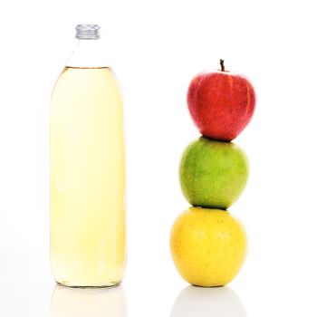 Apple juice in a glass bottle and three ripe apples